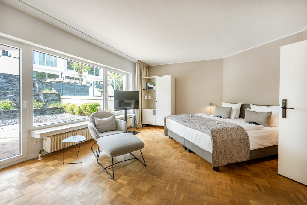 Kabinett-Zimmer im Hotel Kessler-Meyer mit Doppelbett, Sitzbereich, großen Fenstern und Blick ins Grüne
