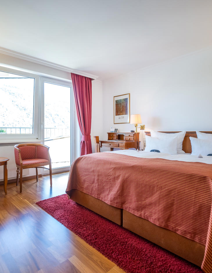 Blick auf das Bett, den Schreibtisch und den Balkon im Zimmer "Auslese mit Balkon und Moselblick"