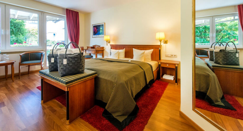 Blick auf das Bett und die gepackten Wellnesstaschen im Zimmer "Auslese mit Südbalkon"