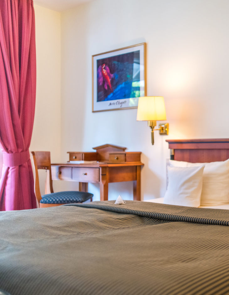 Blick auf das Bett und den Schreibtisch im Zimmer "Auslese mit Südbalkon"