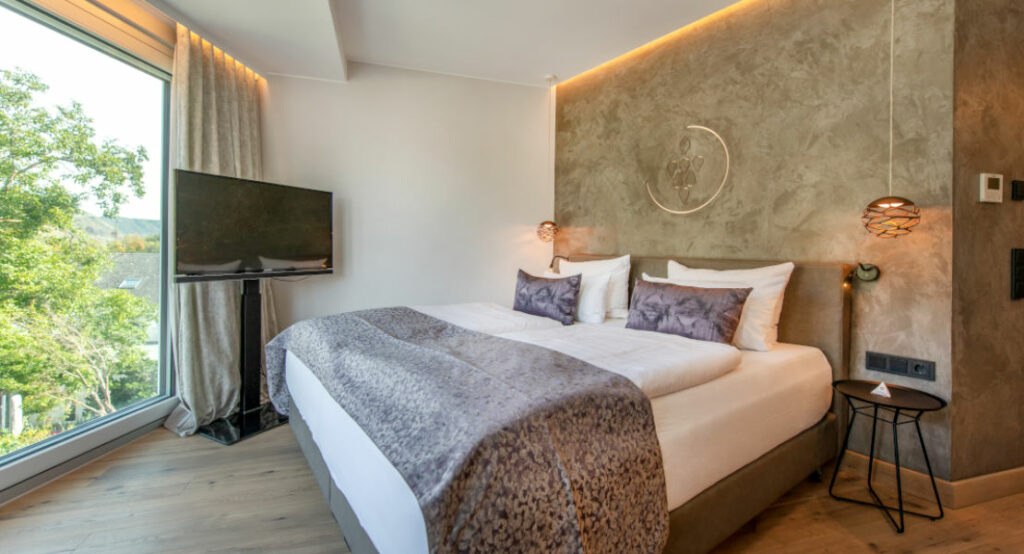 Blick auf das Bett und den Fernseher im Doppelzimmer Riesling