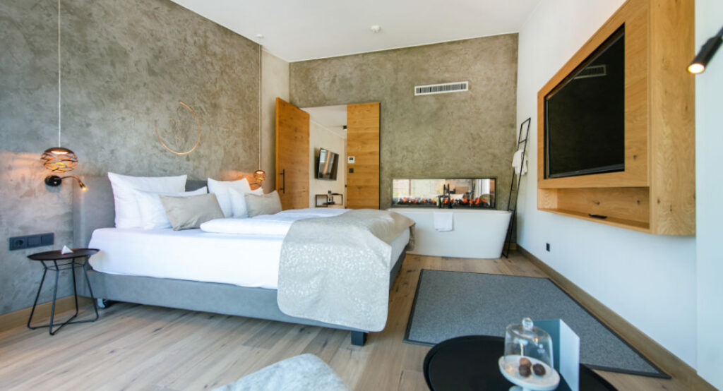 Blick in die Suite Riesling mit Sicht auf das Bett, den Fernseher und die Badewanne