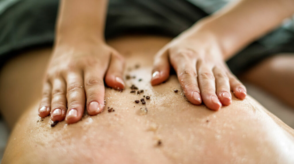 Person bekommt eine Peeling-Massage auf dem Rücken