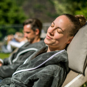 Frau und Mann im Bademantel auf Liegen im Außenbereich