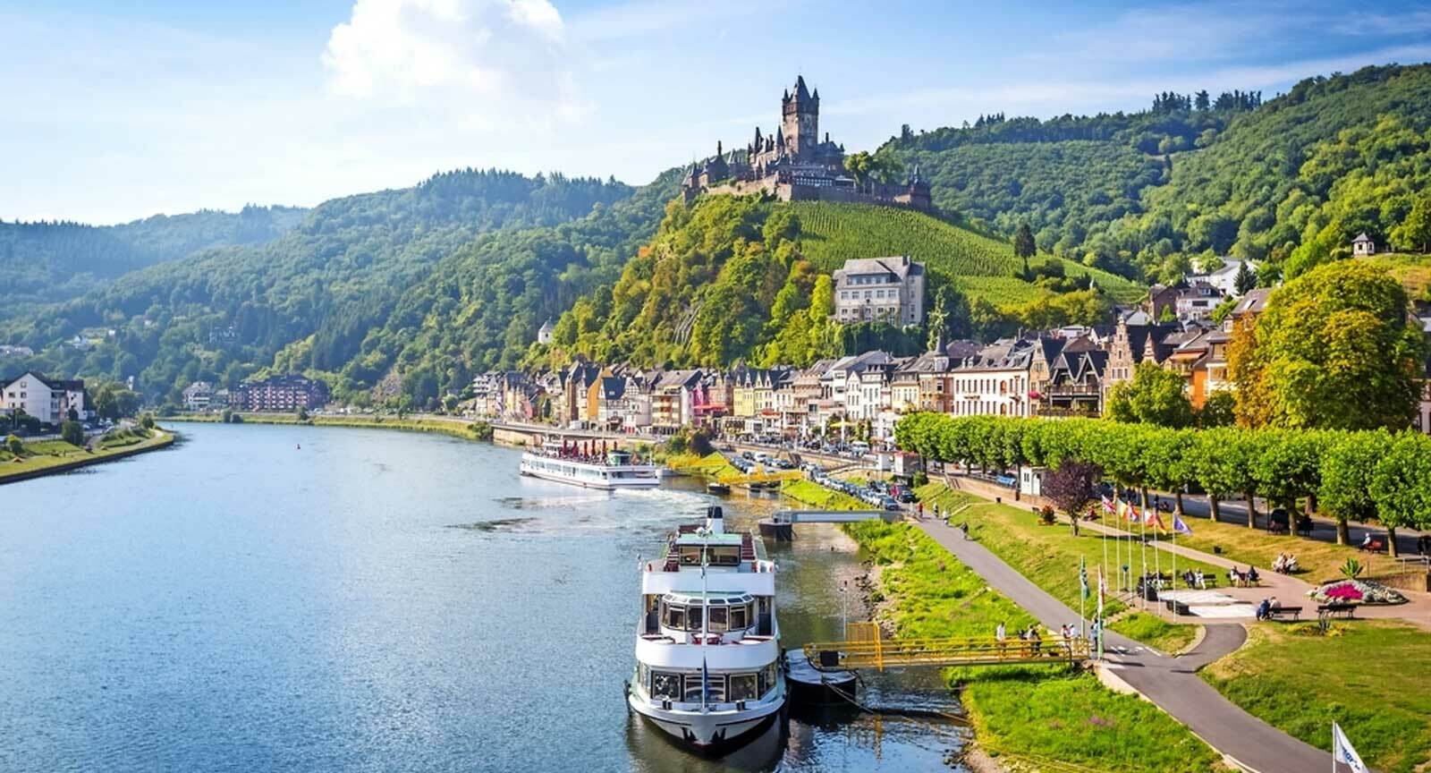 Blick auf die Mosel mit Schiffen, die Uferpromenade von Cochem und die Reichsburg